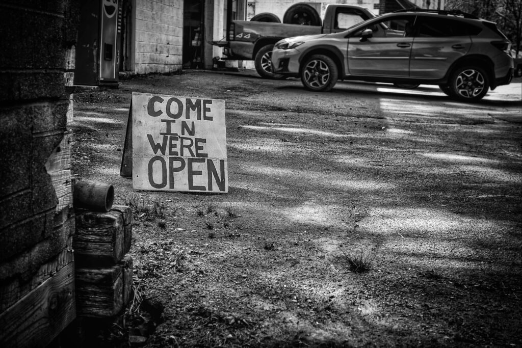 a black and white photo of a hand painted sign that says "come in we're open"