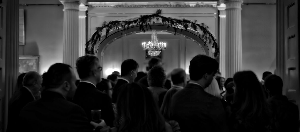 a black and white photo of a grand room full of people.