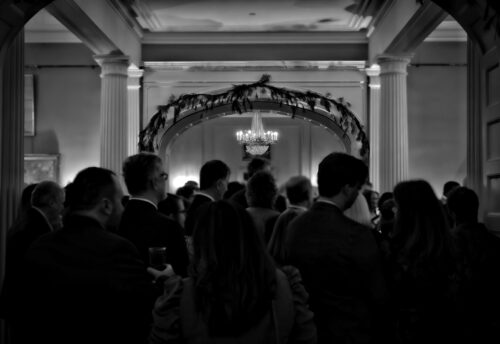 a black and white photo of a grand room full of people.