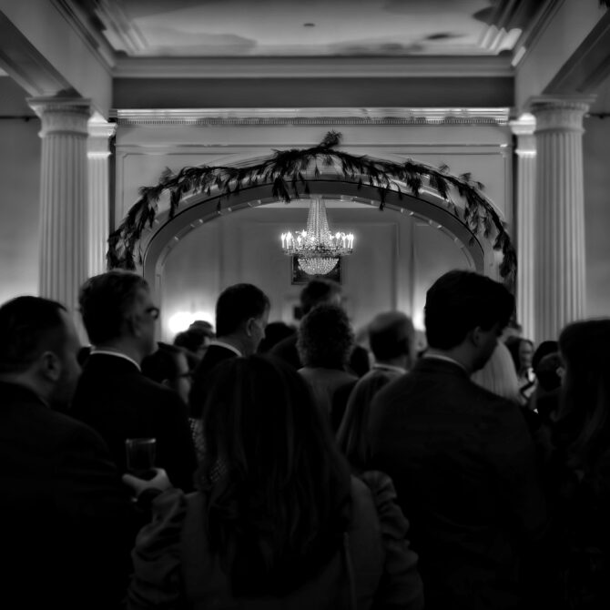 a black and white photo of a grand room full of people.