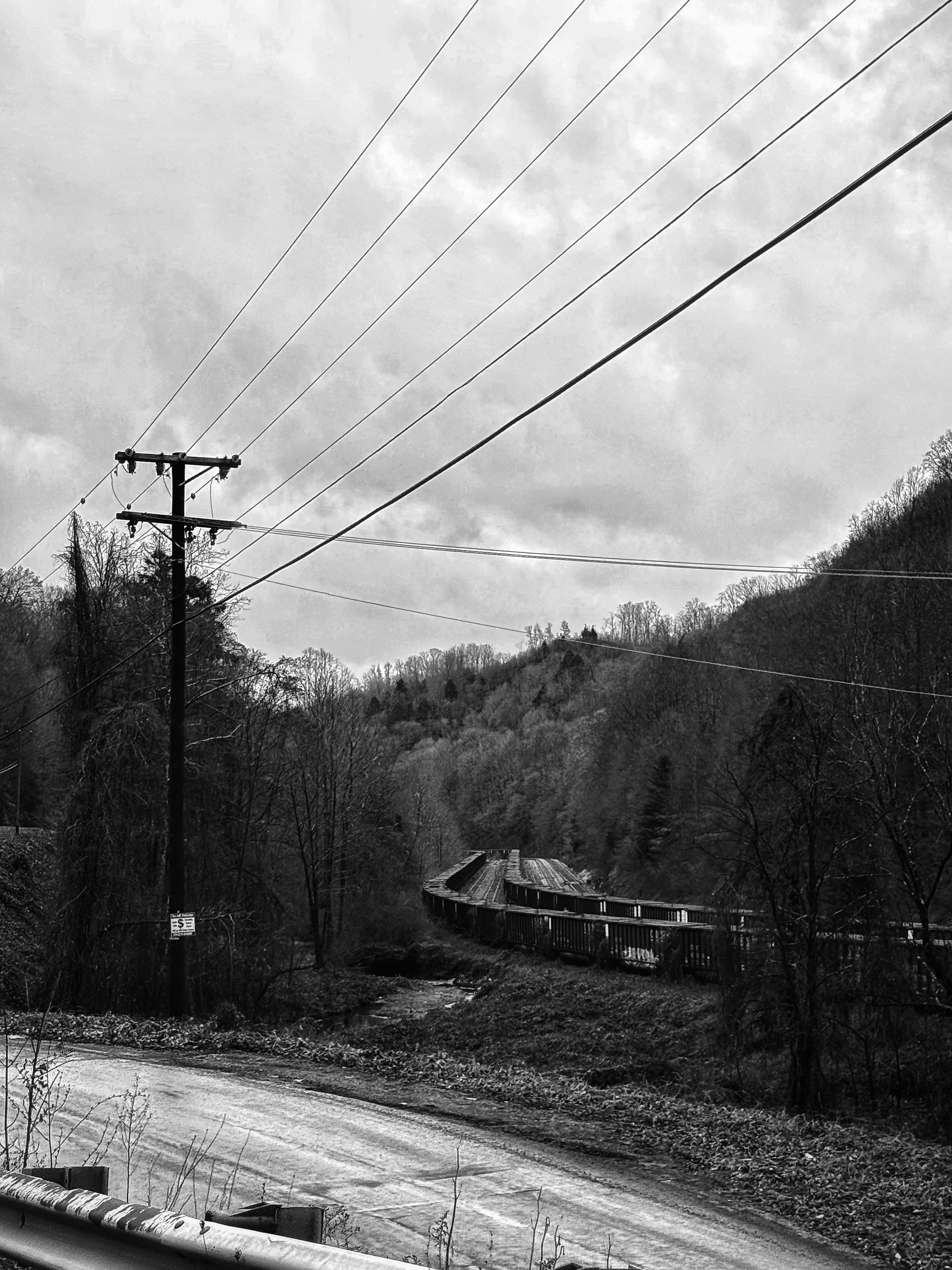 black and white photo of a coal train with power lines overhead